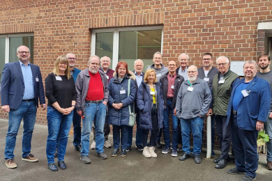 Eine Gruppe von Frauen und Männern steht vor einem Gebäude aus Backstein