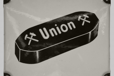 weißes Emaileschild mit schwarzen Brikett mit Schriftzug Union-Brikett