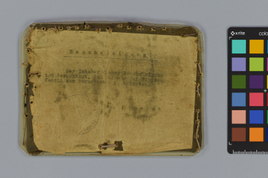 Schriftstück auf dünnem Papier, eingenäht zwischen Kunststoff und gummierten Stoff mit unregelmäßigen Löchern
