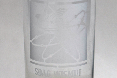 Bierglas mit Gravur eines stilisierten Atoms drei Umlaufbahnen und eine Taube sowie Schriftzug 