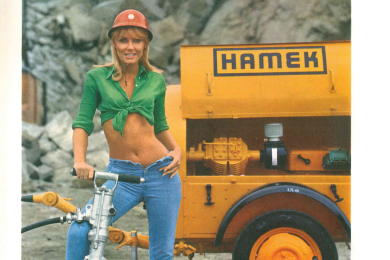 Frau mit bauchfreiem Top mit Grubenhelm hält einen Bohrhammer fest