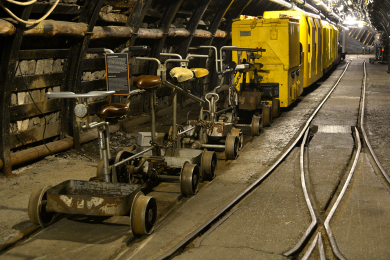 Vier unterschiedliche Grubenräder in der Flözstrecke des Anschauungsbergwerks des Deutschen Bergbau-Museums Bochum hintereinander auf den Schienen stehend.
