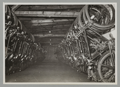 Fotografie vieler Fahrräder in einem Raum vertikal in Reihe nebeneinander hängend.