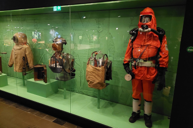 Das Bild zeigt eine Figurine mit der modernen Schutzausrüstung eines Grubenwehrmanns in einer Vitrine in der Dauerausstellung des Deutschen Bergbau-Museums Bochum