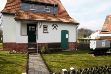 Ein freistehendes Haus mit rotem Ziegeldach und einem Förderwagen vor der Tür