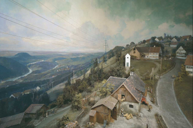 Ein Diorama mit einem Dorf in einer Gebirgslandschaft und einer Stromleituung