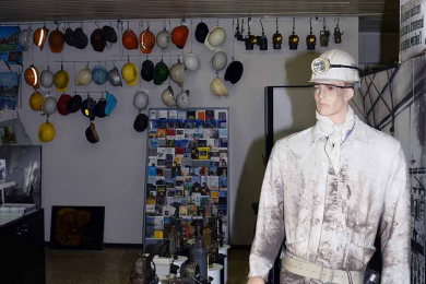 Sammlungsraum mit Figur eines modernen Bergmanns im Vordergrund und eine Sammlung von Helmen im Hintergrund