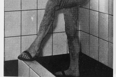 Bergmann unter der Dusche, an seinen Füßen Kauenlatschen 