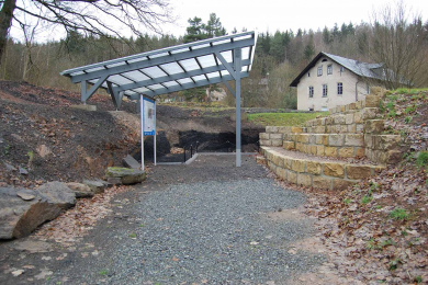 Zu sehen sind das Geotop mit Kohleaufschluss und die alte Rentei im Hintergrund