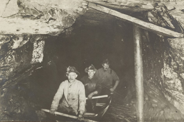 Drei Männer in einem Holzkahn bei der Befahrung eines Stollens im Jahr 1932