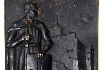 Kleines rechteckiges Relief aus Eisenguss, im Vordergrund ein Ritter mit Schild und Schwert, im Hintergrund eine Burg an einem Fluss, oben die Jahreszahl 1942.