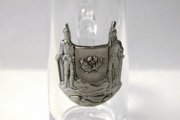 Schnapsglas mit Zinnrelief zeigt zwei Bergleute und ein Wappenschild 