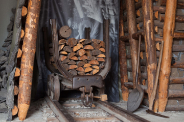 Ein aus Holz gezimmerter Streckenausbau mit einem mit Holz beladenen Förderwagen
