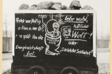 Karikatur auf einem Förderwagen mit einem aus einem Klosett schauenden Bergmann. 