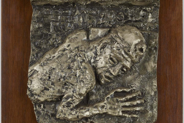  Das Aluminiumrelief zeigt den Oberkörper eines Bergmannes, der mit aller Kraft einen Wagen schiebt.