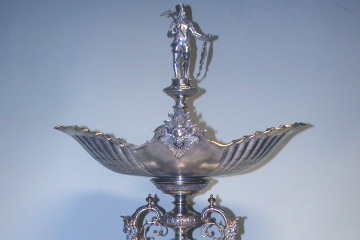 Ein kunstvoll verzierter, silberner Tafelaufsatz mit vier Schalen zur Aufnahme z.B. von Früchten und einer Bergmannsfigur an der Spitze