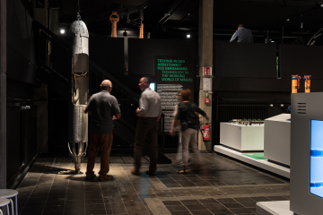 Museumsraum mit Besuchenden und Exponaten, darunter eine Rettungskapsel