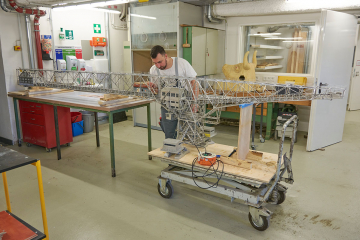 Ein Mann arbeitet in der Werkstatt des Deutschen Bergbau-Museums Bochum mit einem Pinsel an einem Modell einer großen technischen Vorrichtung im Bergbau zum Transport von Fördergut über den offenen Tagebau hinweg