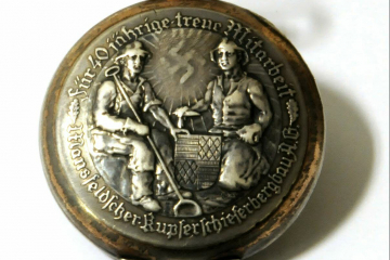 Rückendeckel einer Taschenuhr mit zwei Bergleuten, Wappen, Hackenkreuz und Umschrift