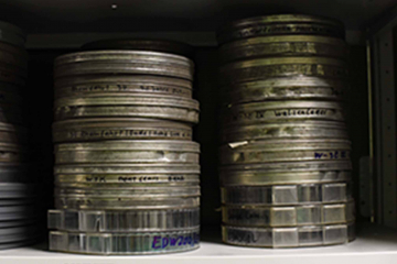 Das Symbolbidl zur Filmvorführung & Podiumsdiskussion „After Coal“ zeigt zwei Stapel mit Filmdosen in einem Archivregal.