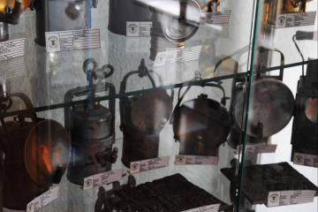 Das Foto zeigt eine Sammlung von historischem Grubengleucht in einer Vitrine.