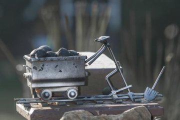 Zu sehen ist eine kleine Metallskulptur, die einen Bergmann mit einem Kohlewagen darstellt.