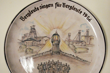 Ein Porzellan-Wandteller mit Zechenanlagen, einer Grubenlampe und einem Bergmannschor