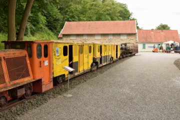 Blick auf das noch nicht zerstörte Ausstellungsgebäude, im Vordergrund eine Grubenbahn