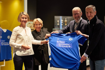 Drei Personen in der Ausstellung halten das Trikot